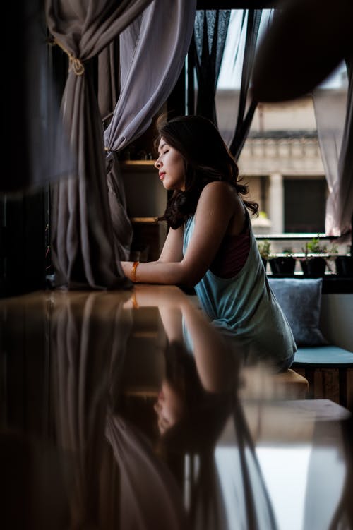 绿色无袖连衣裙坐在棕色的木桌上的女人 · 免费素材图片