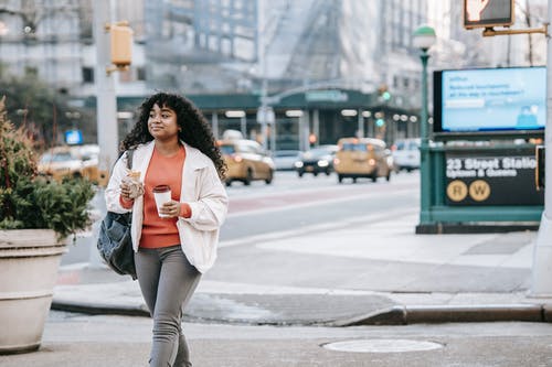 白色外套和灰色的裤子，站在人行道上的女人 · 免费素材图片