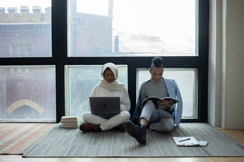 男人和女人坐在地板上使用macbook · 免费素材图片