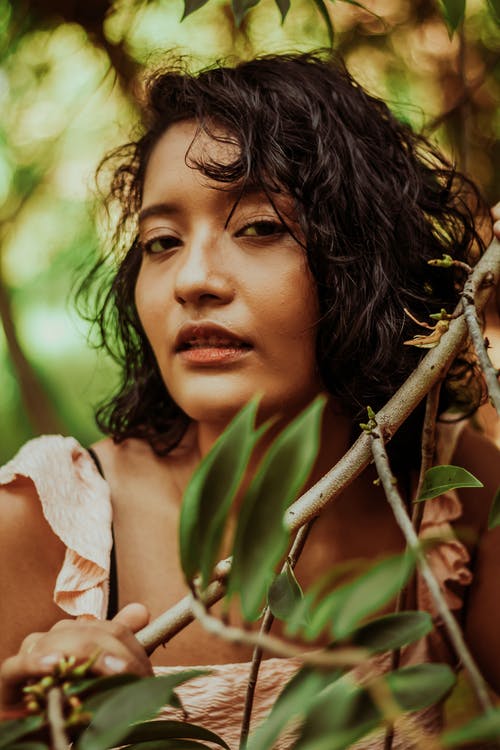 拿着棕色树枝的白色无袖连衣裙的女人 · 免费素材图片