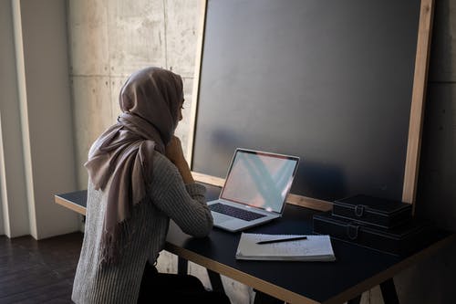 坐在便携式计算机前的棕色头巾的女人 · 免费素材图片