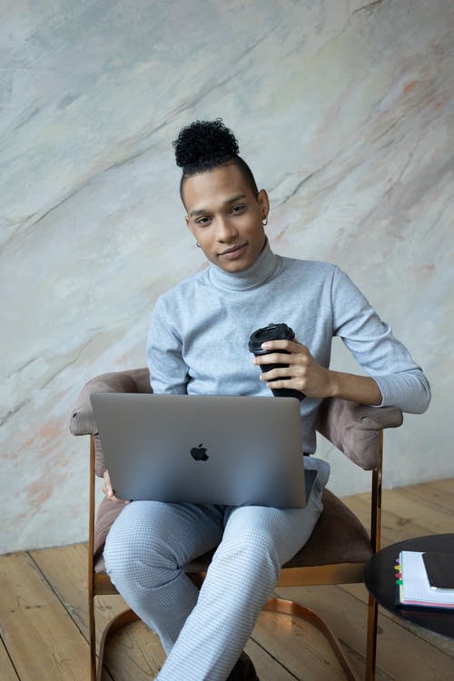 坐在椅子上，使用macbook的灰色毛衣的男人 · 免费素材图片