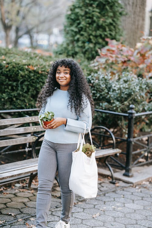 白色长袖衬衫和灰色的裤子，拿着束鲜花的女人 · 免费素材图片