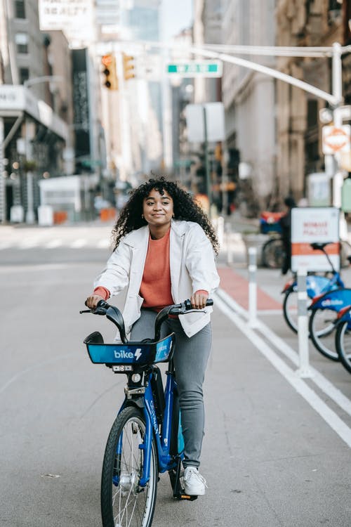 白色长袖衬衫骑在蓝色自行车上的女人 · 免费素材图片