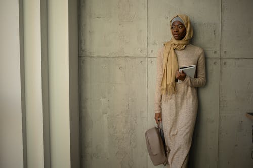 站在白墙旁边的米色头巾的女人 · 免费素材图片