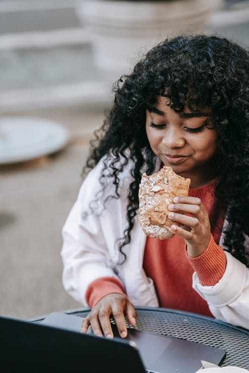 白色长袖衬衫吃面包的女孩 · 免费素材图片