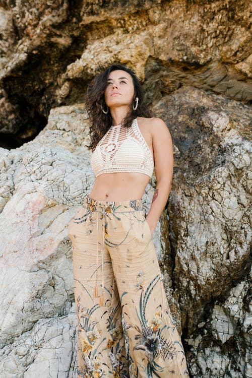 白色吊带衫顶部和米色裤子站在灰色岩石旁边的女人 · 免费素材图片