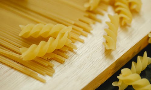 棕色的木桌上的黄色面食 · 免费素材图片