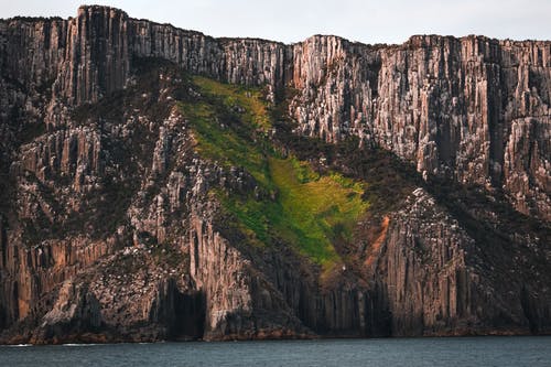 水体旁边的棕色和绿色山 · 免费素材图片