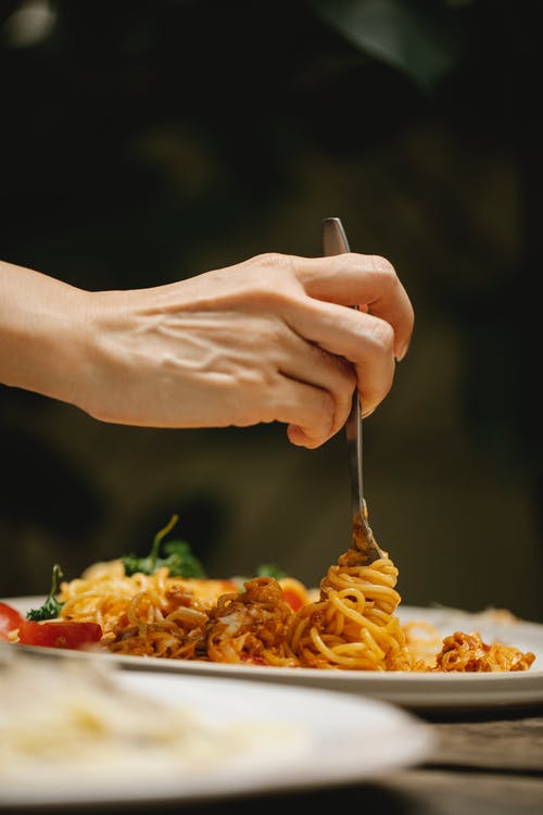 持有银叉和面食的人 · 免费素材图片