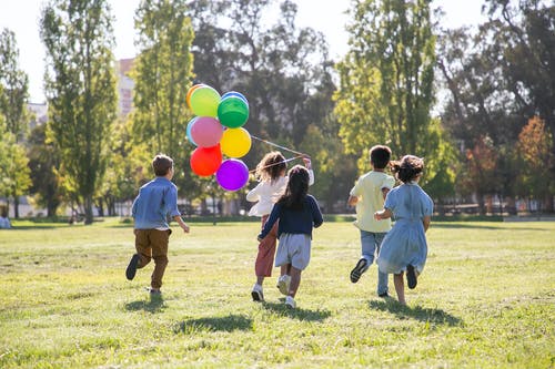 孩子们在玩气球在绿色草地上 · 免费素材图片