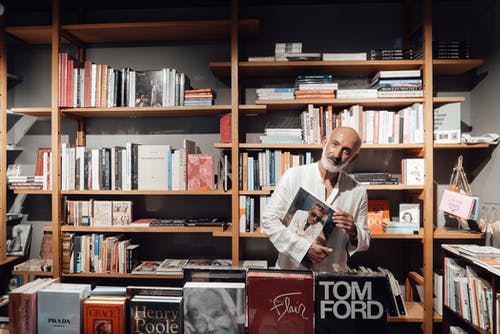 站在书旁边的白色礼服衬衫的男人 · 免费素材图片