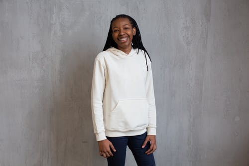 白色长袖衬衫和蓝色牛仔牛仔裤，站在灰色的墙旁边的女人 · 免费素材图片