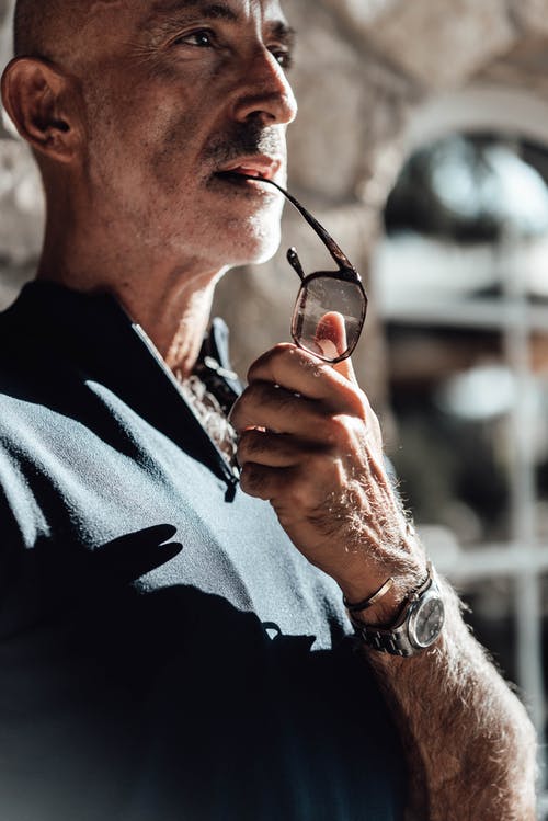 拿着眼镜的黑色毛衣的男人 · 免费素材图片