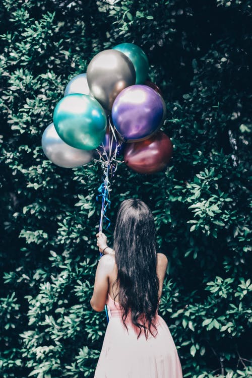女人抱着蓝色和绿色的气球 · 免费素材图片
