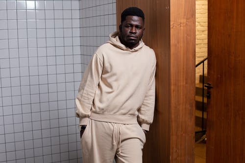 站在棕色木门附近的白色连帽衫的男人 · 免费素材图片