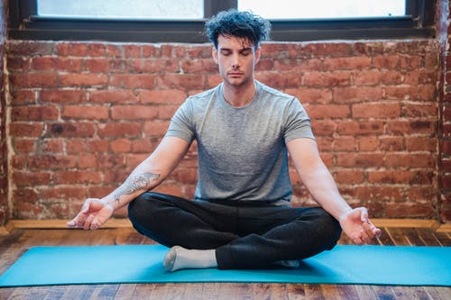 穿着灰色圆领t恤和黑色的裤子，坐在蓝色瑜伽垫上的男人 · 免费素材图片