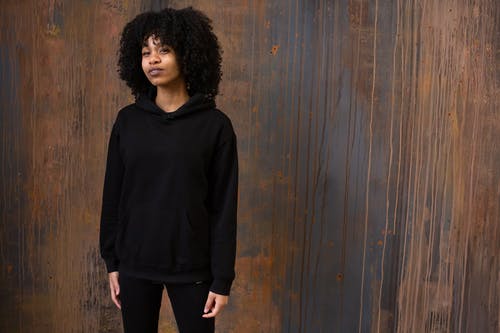 黑色长袖衬衫和黑色的裤子，站在棕色木墙旁边的女人 · 免费素材图片