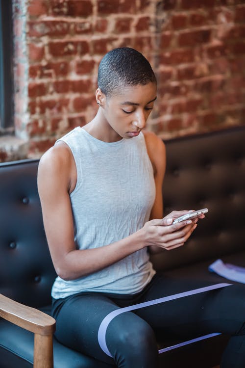 白色背心和蓝色牛仔牛仔裤，坐在黑色的木凳上的男人 · 免费素材图片