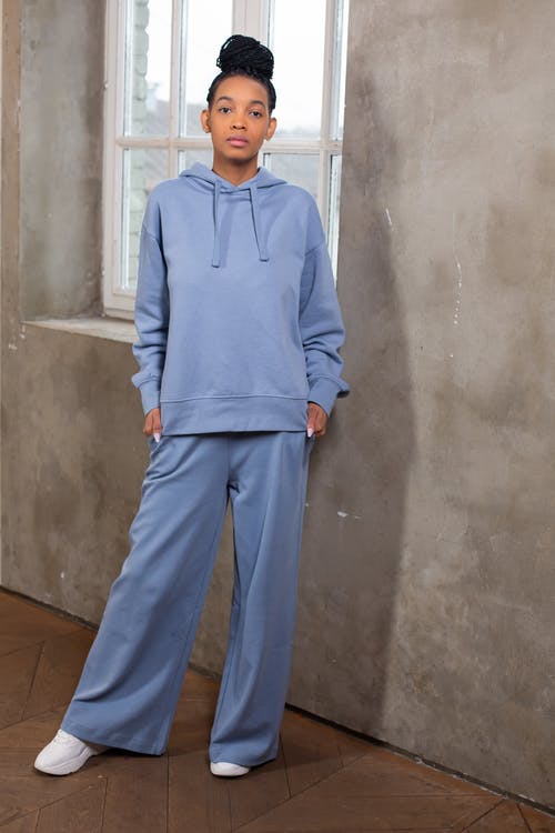 站在灰色墙上的蓝色连帽衫的男人 · 免费素材图片