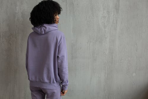 站在灰色墙边的紫色连帽衫的男人 · 免费素材图片