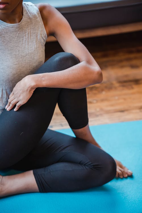 坐在蓝色瑜伽垫上的黑色紧身裤的女人 · 免费素材图片