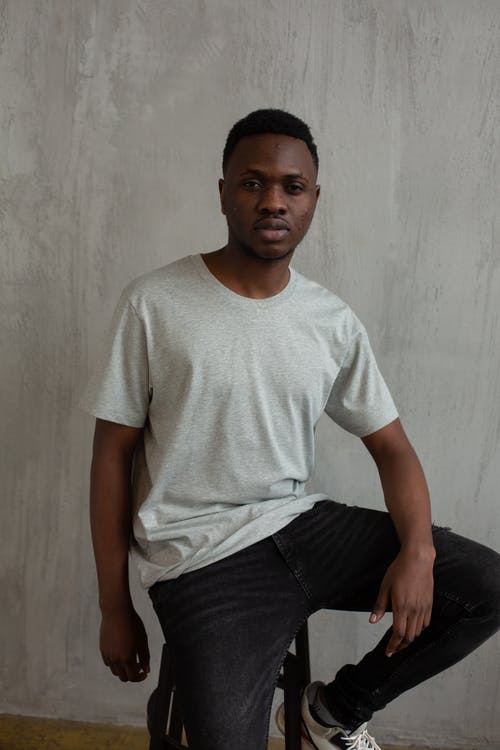 白船员的脖子t恤和黑色的裤子，坐在黑色的椅子上的人 · 免费素材图片