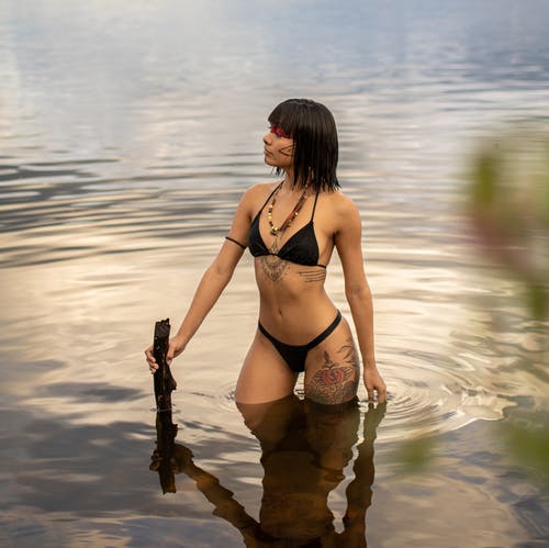 在海滩上散步的黑色比基尼的女人 · 免费素材图片