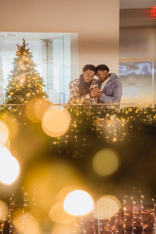 男人和女人在圣诞树旁接吻 · 免费素材图片