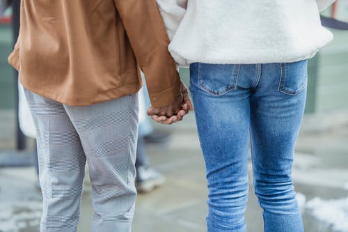 男人和女人在街上散步时手牵着手 · 免费素材图片