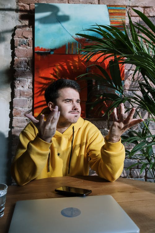 坐在椅子上的黄色连帽衫的男人 · 免费素材图片