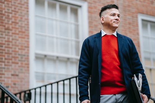 黑色西装外套和红色衬衫站在黑色金属栅栏附近的人 · 免费素材图片