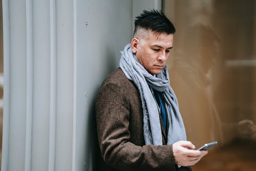 站在白墙附近的灰色外套的男人 · 免费素材图片