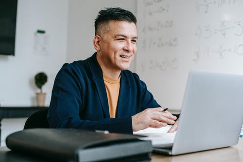 蓝色长袍的男人坐在椅子上，使用macbook · 免费素材图片