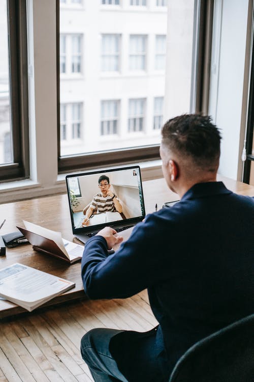 坐在餐桌旁使用macbook的黑色长袖衬衫的男人 · 免费素材图片