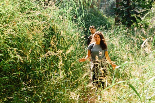 白色t恤和黑色的裙子，在绿色草地上行走的女人 · 免费素材图片