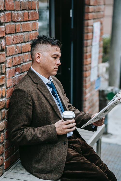 拿着白色陶瓷杯子的棕色衣服夹克的人 · 免费素材图片