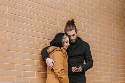 黑色长袖衬衫的男人拥抱棕色外套的女人 · 免费素材图片