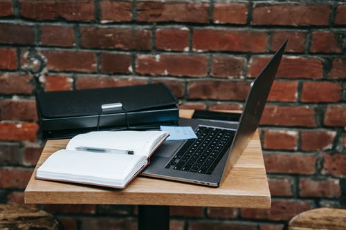 棕色木制的桌子上的黑色和灰色便携式计算机旁边的黑色和银色便携式计算机 · 免费素材图片