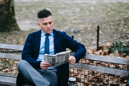 蓝色西装外套阅读本书坐在棕色的木凳上的男人 · 免费素材图片