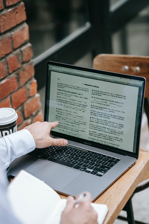 在棕色的木桌上使用macbook Pro的人 · 免费素材图片