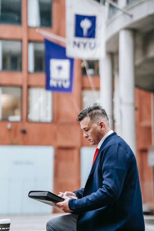 站在白色和棕色建筑附近的蓝色西装外套的男人 · 免费素材图片