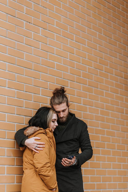 黑色长袖衬衫的男人拥抱棕色皮夹克的女人 · 免费素材图片