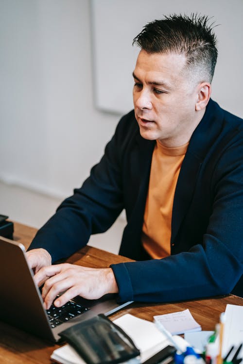 使用macbook的蓝色长袖衬衫的男人 · 免费素材图片