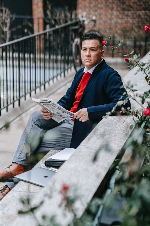 黑色和蓝色外套拿着报纸的人 · 免费素材图片