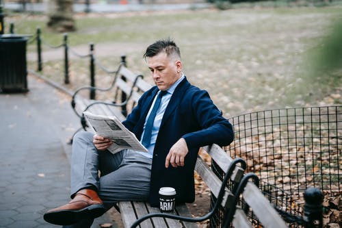 蓝色西装外套的人坐在长椅上看书 · 免费素材图片