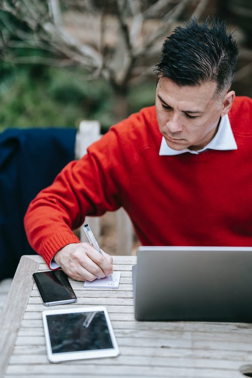 使用银色macbook的红色毛衣的男人 · 免费素材图片
