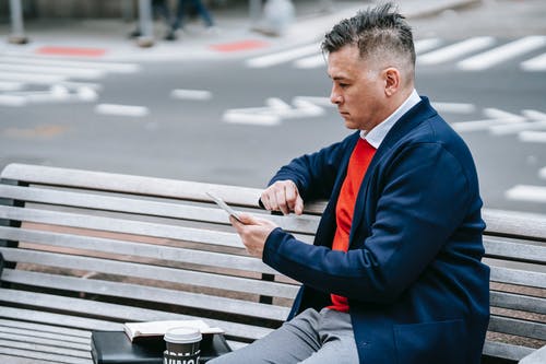 坐在长凳上的蓝色西装外套的男人 · 免费素材图片