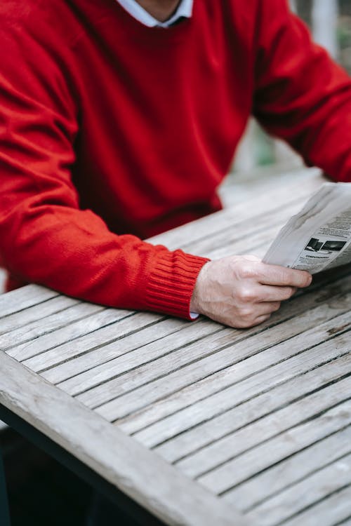 拿着白皮书的红色长袖衬衫的人 · 免费素材图片
