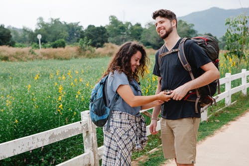 男人和女人在绿草地上行走时手牵着手 · 免费素材图片